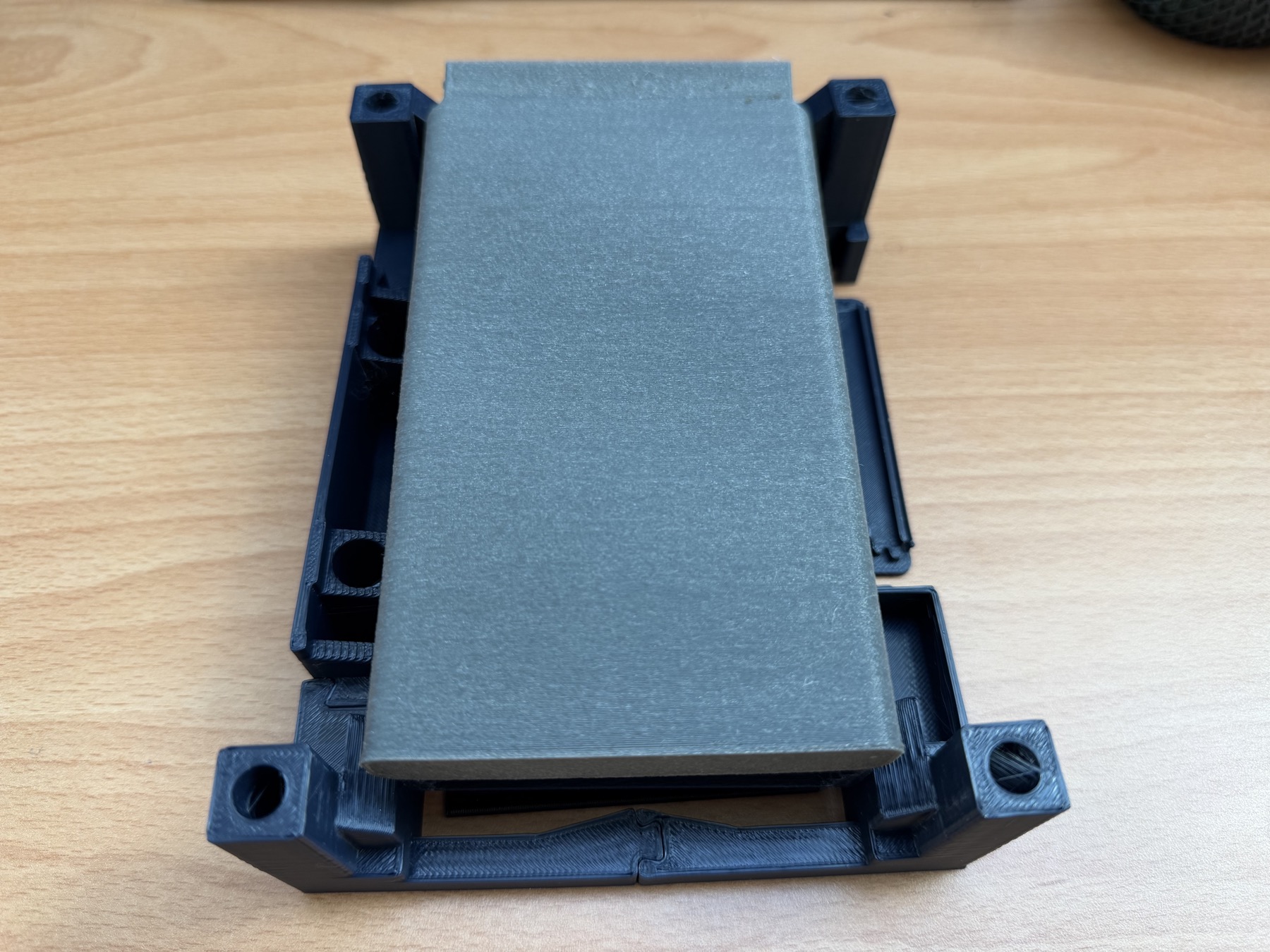 A physical printed stand prototype reveals the corner modules, rails, and central interlock from the back.